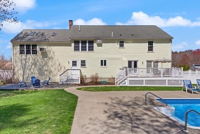rear view of property with fence, a deck, a chimney, a patio area, and a lawn