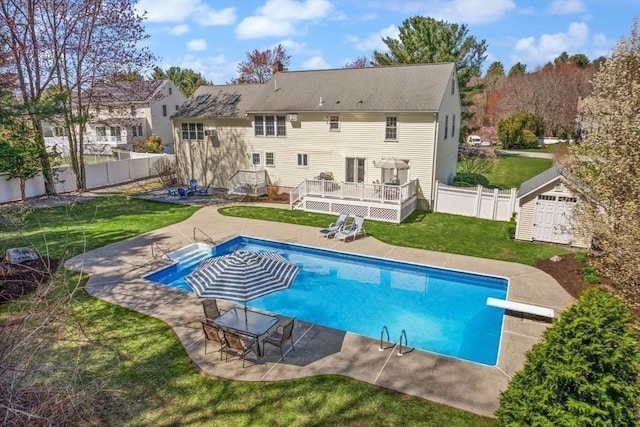 back of house with a storage shed, a deck, a fenced backyard, a lawn, and an outdoor structure