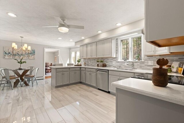 kitchen featuring a sink, light countertops, a peninsula, decorative backsplash, and stainless steel dishwasher