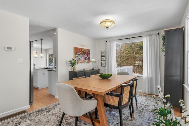 dining room with light wood-type flooring, visible vents, and baseboards