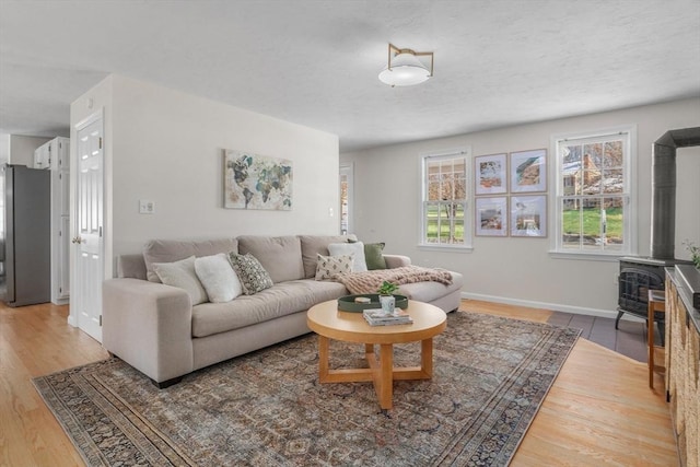 living room with a wood stove, baseboards, and wood finished floors