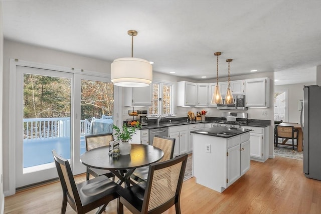 kitchen featuring appliances with stainless steel finishes, white cabinetry, and decorative light fixtures