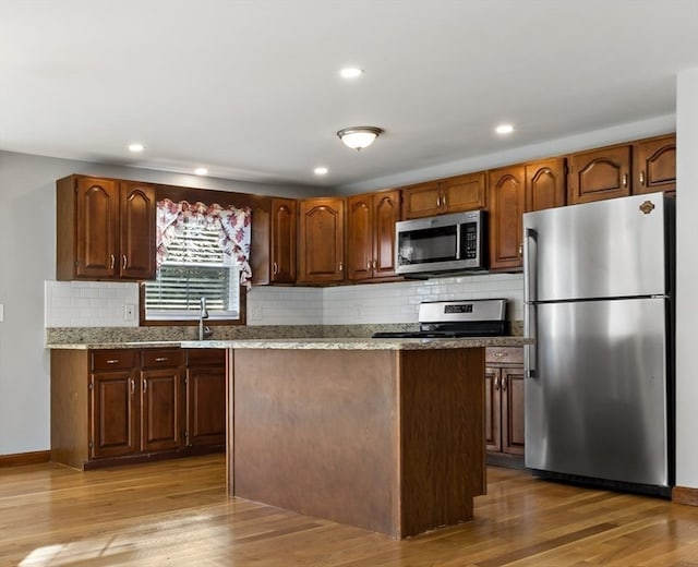 kitchen with stainless steel appliances, tasteful backsplash, and light wood-type flooring