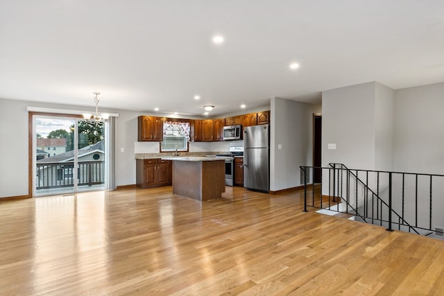 kitchen with hanging light fixtures, light wood-type flooring, appliances with stainless steel finishes, and a center island