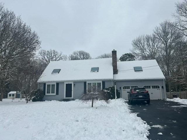 view of front of property with a garage, a chimney, and aphalt driveway