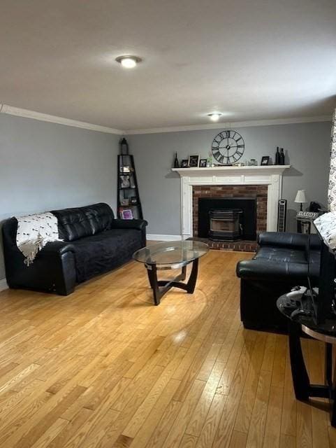 living area featuring baseboards, wood-type flooring, a fireplace, and crown molding