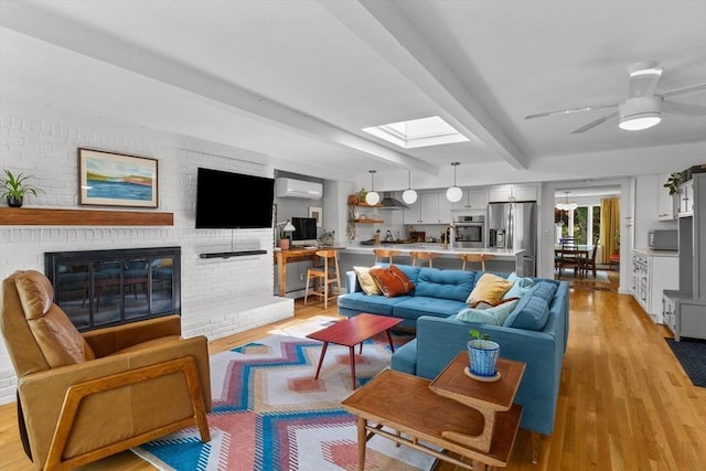 6 Hayes Rd, Salem, MA 01970 - living area with an AC wall unit, light wood finished floors, beamed ceiling, a fireplace, and a skylight