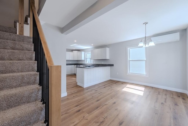 46 Lyons St, Lowell, MA 01852 - kitchen featuring a wall unit AC, open floor plan, white cabinets, light wood-style floors, and dark countertops