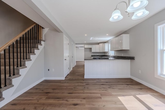 46 Lyons St, Lowell, MA 01852 - kitchen with dark countertops, baseboards, white cabinetry, a peninsula, and wood finished floors