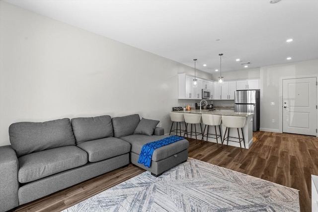 living area featuring dark wood-style flooring, baseboards, and recessed lighting