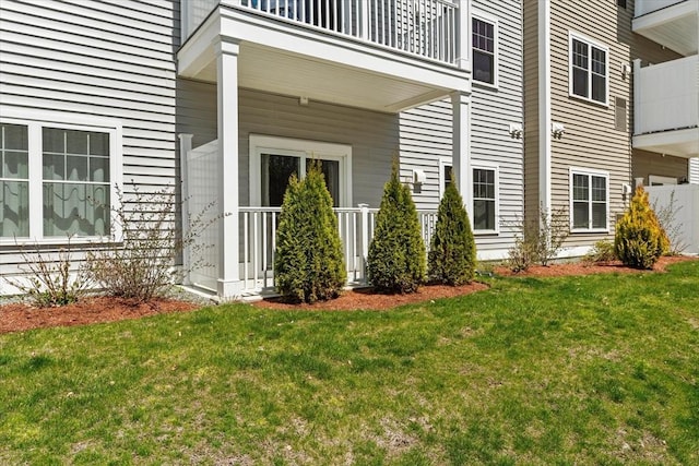 property entrance with a lawn and a balcony