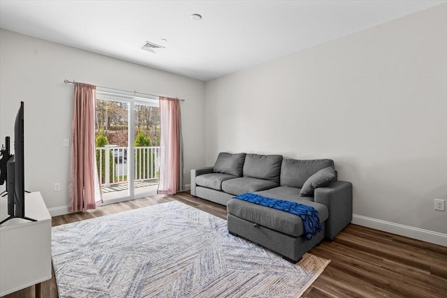 living area with baseboards, visible vents, and wood finished floors