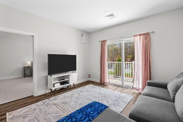 living area with baseboards, visible vents, and wood finished floors