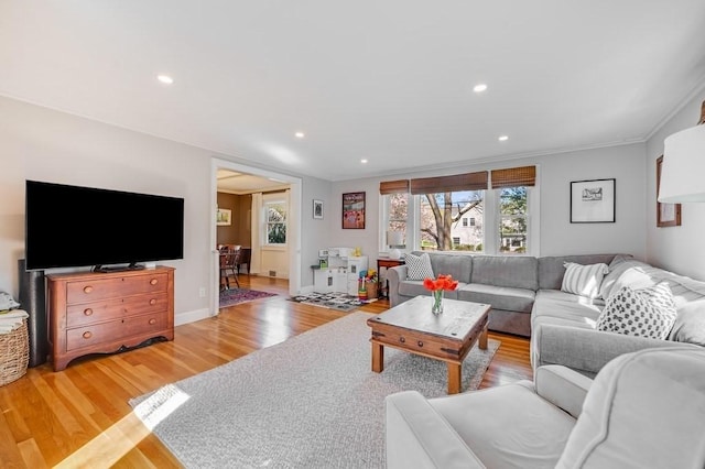 living area featuring light wood-style floors, ornamental molding, baseboards, and recessed lighting