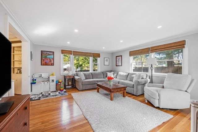 living room with plenty of natural light, ornamental molding, and light wood-style flooring