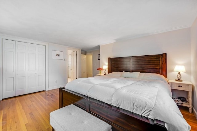 bedroom with crown molding, baseboards, light wood finished floors, and a closet