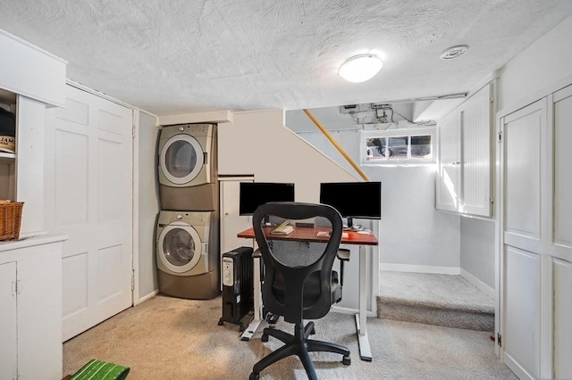 office featuring a textured ceiling, baseboards, light colored carpet, and stacked washer / dryer