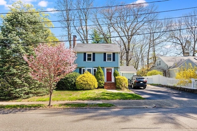 view of front of property with fence, a chimney, and aphalt driveway