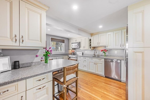 kitchen with light wood-style floors, recessed lighting, light countertops, a sink, and appliances with stainless steel finishes