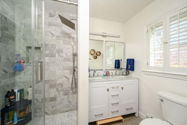 bathroom featuring toilet, a stall shower, double vanity, and tile patterned flooring