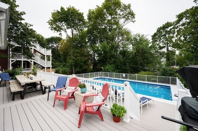 view of swimming pool featuring outdoor dining space, view of scattered trees, and a deck
