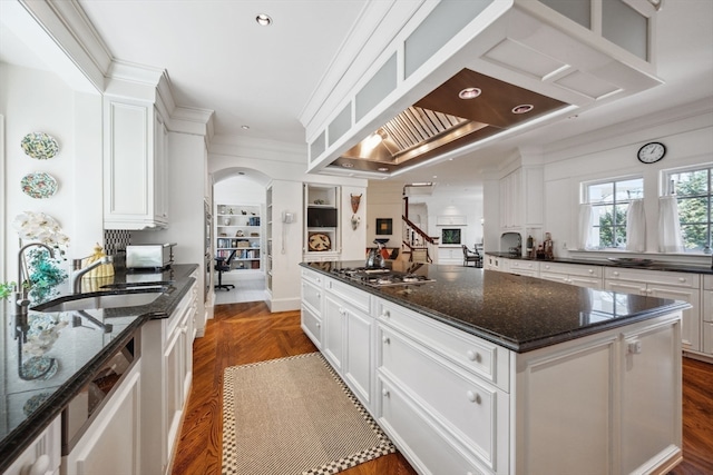 kitchen with white cabinets, sink, a center island, and dark stone counters