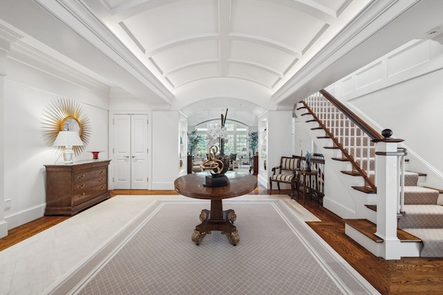 foyer with hardwood / wood-style floors, beamed ceiling, ornamental molding, and coffered ceiling