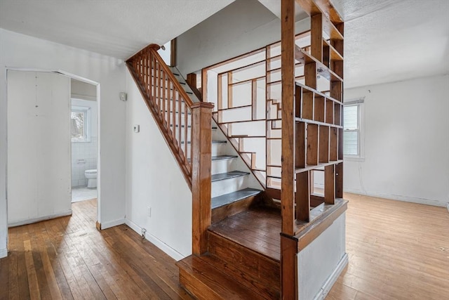 staircase with wood-type flooring, a textured ceiling, and baseboards