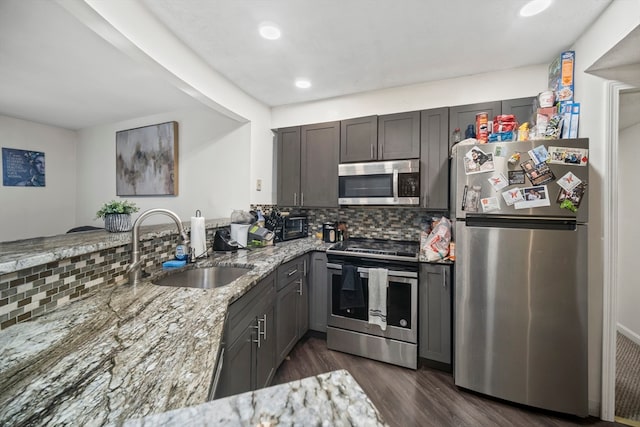 kitchen with appliances with stainless steel finishes, tasteful backsplash, sink, light stone counters, and dark hardwood / wood-style floors