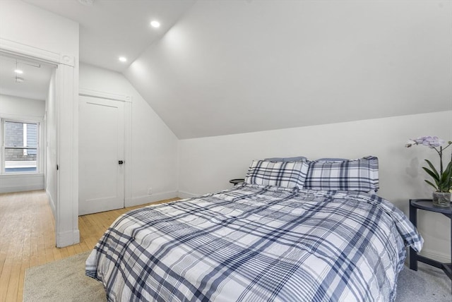 bedroom featuring a closet, vaulted ceiling, and light wood-type flooring