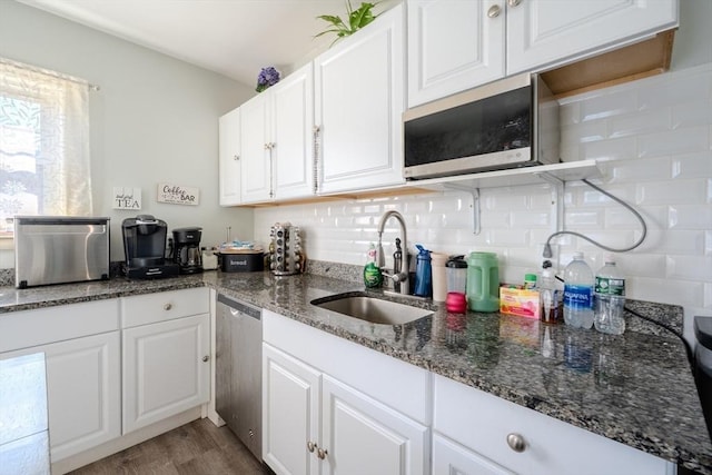 69-71 Pond St, Waltham, MA 02451 - kitchen featuring appliances with stainless steel finishes, a sink, white cabinets, tasteful backsplash, and wood finished floors
