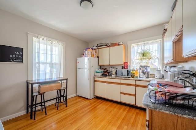 69-71 Pond St, Waltham, MA 02451 - kitchen with freestanding refrigerator, stainless steel microwave, light wood-style floors, a sink, and white cabinetry