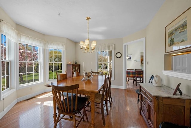 dining space featuring hardwood / wood-style flooring, a notable chandelier, baseboards, and visible vents