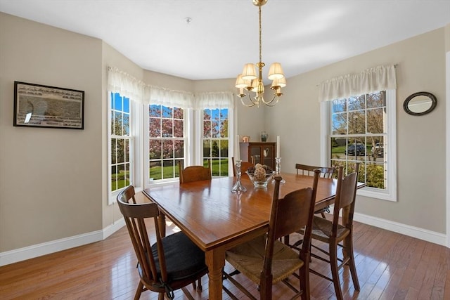 dining space with baseboards, hardwood / wood-style floors, and an inviting chandelier