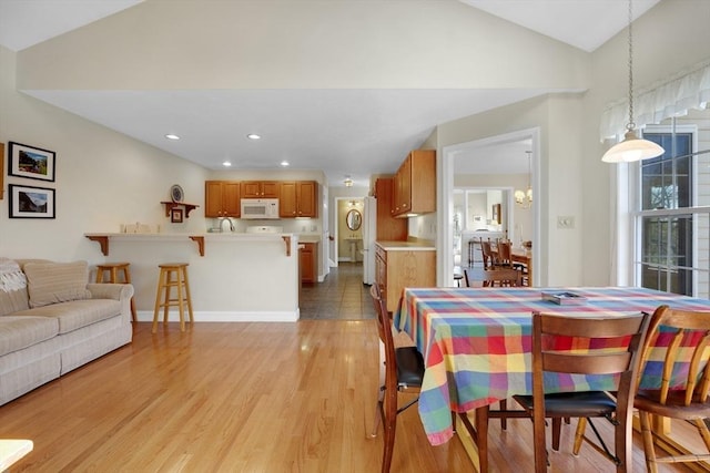 dining space with vaulted ceiling, recessed lighting, baseboards, and light wood-style floors