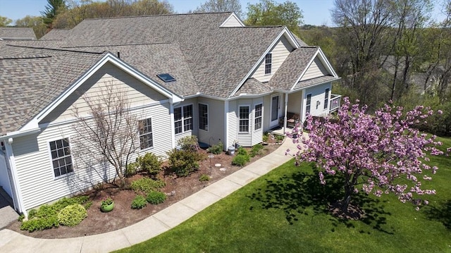 cape cod home with a front yard and roof with shingles