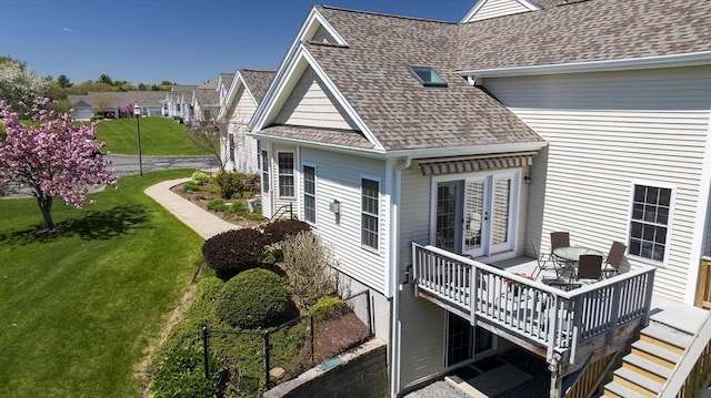 view of side of property with a shingled roof, a yard, and a deck