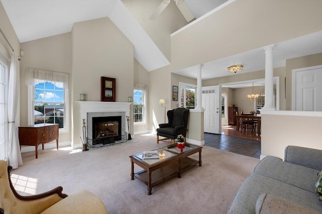 carpeted living area with a premium fireplace, baseboards, high vaulted ceiling, and decorative columns