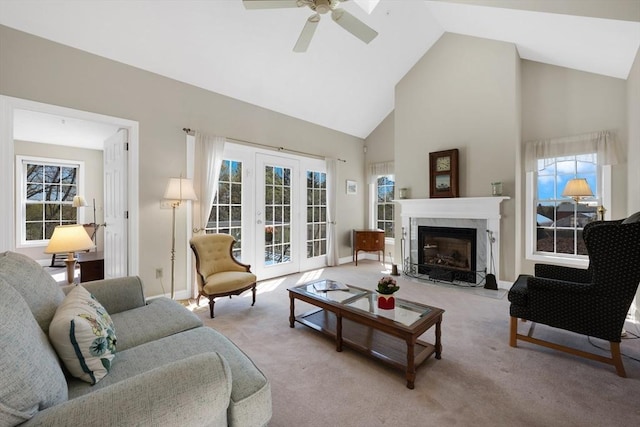 living area featuring a high end fireplace, light colored carpet, high vaulted ceiling, a ceiling fan, and baseboards