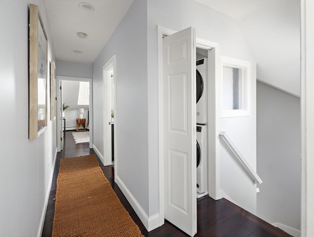 hall with an upstairs landing, baseboards, dark wood finished floors, and stacked washer / dryer