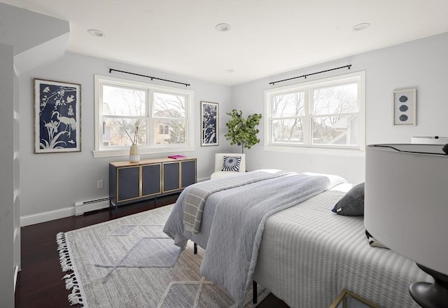 bedroom featuring dark wood finished floors, multiple windows, a baseboard heating unit, and baseboards