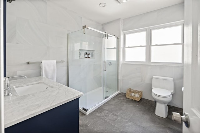 bathroom with vanity, a shower stall, toilet, and tile walls