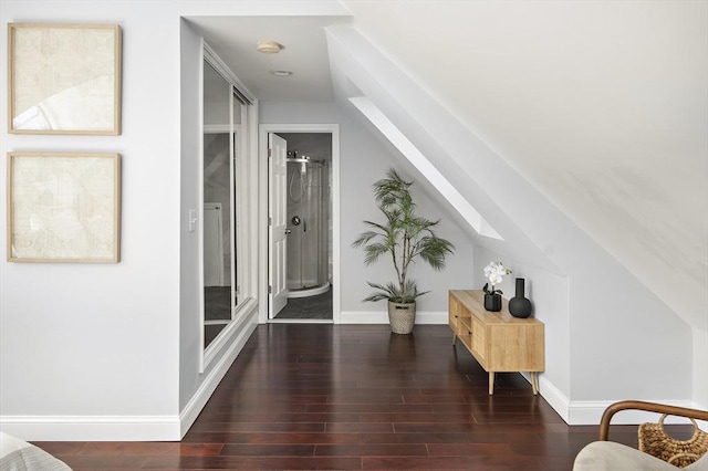 hall with lofted ceiling with skylight, wood finished floors, and baseboards