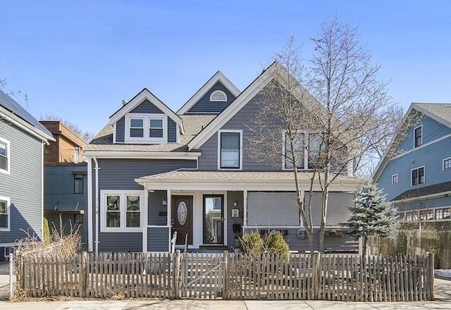 view of front of property with a fenced front yard, covered porch, and roof with shingles