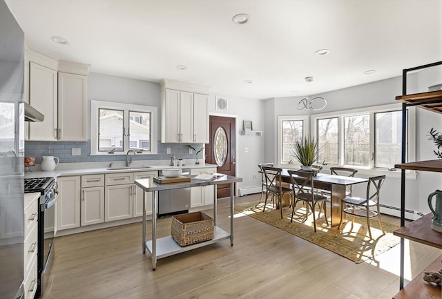 kitchen with gas stove, light wood-type flooring, decorative backsplash, and a sink