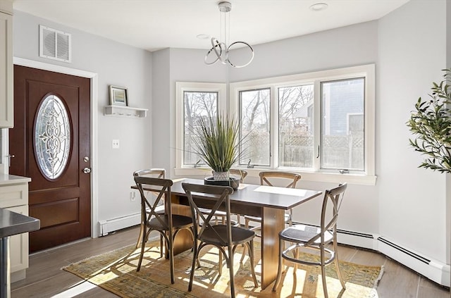 dining area with visible vents, wood finished floors, and a baseboard heating unit