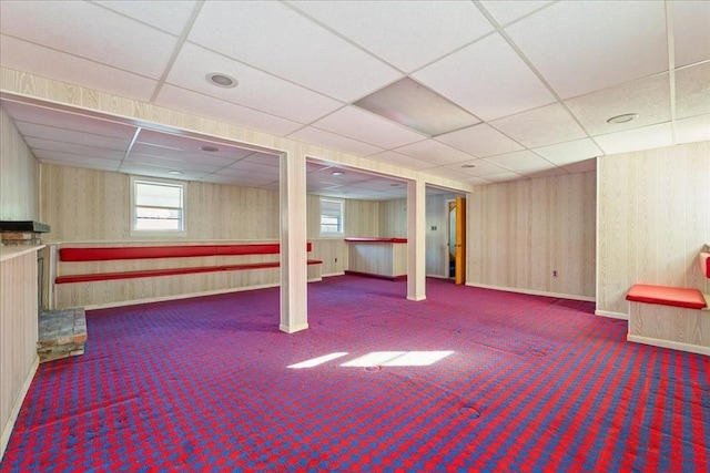 basement with a paneled ceiling and dark colored carpet