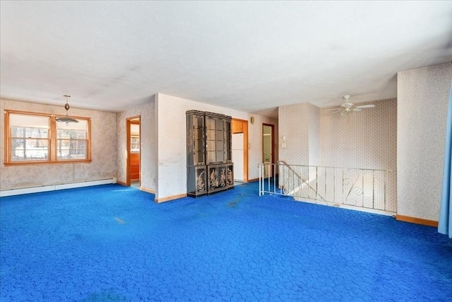 spare room featuring ceiling fan, a baseboard heating unit, and dark carpet