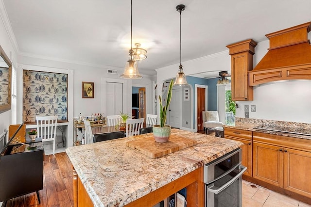 19 Brown Ct, Methuen, MA 01844 - kitchen featuring a center island, black electric cooktop, ceiling fan, ornamental molding, and brown cabinetry