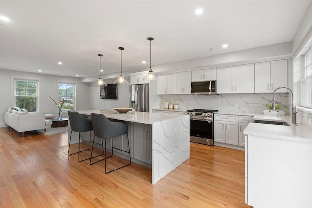 114 Broad St Unit D, Weymouth, MA 02188 - kitchen featuring stainless steel appliances, a sink, a kitchen island, light wood-style floors, and white cabinetry